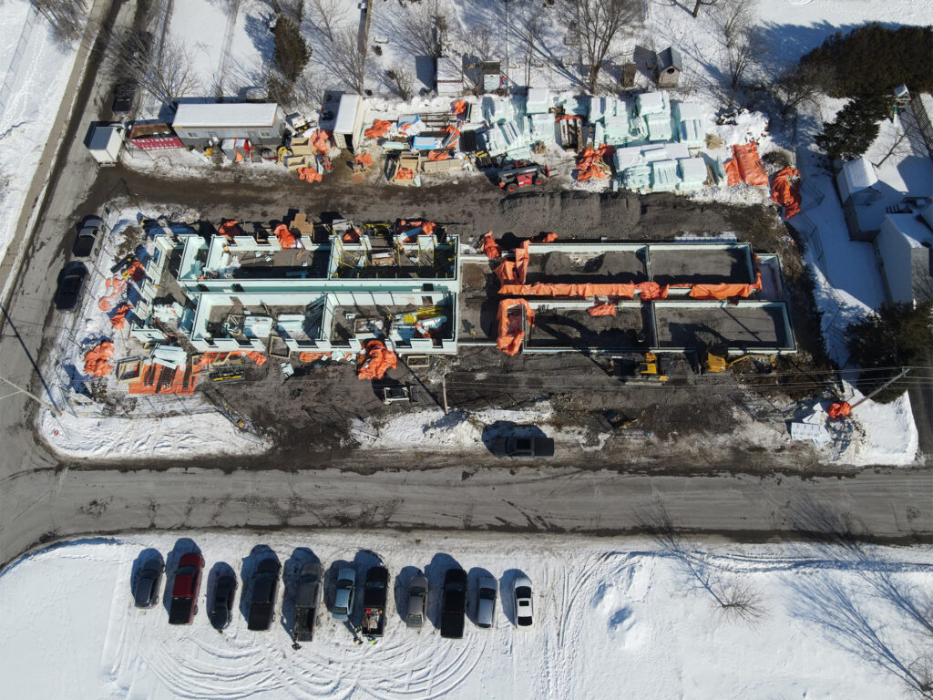 Aerial view of a snowy construction site with exposed building foundations