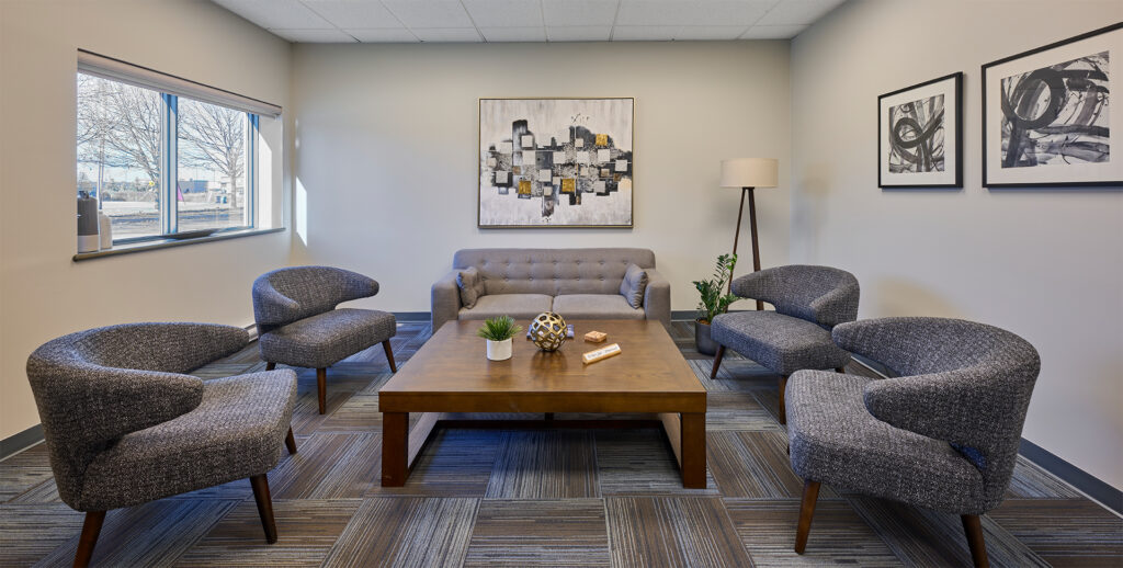 A tastefully decorated lobby with a gray upholstered sofa and matching armchairs