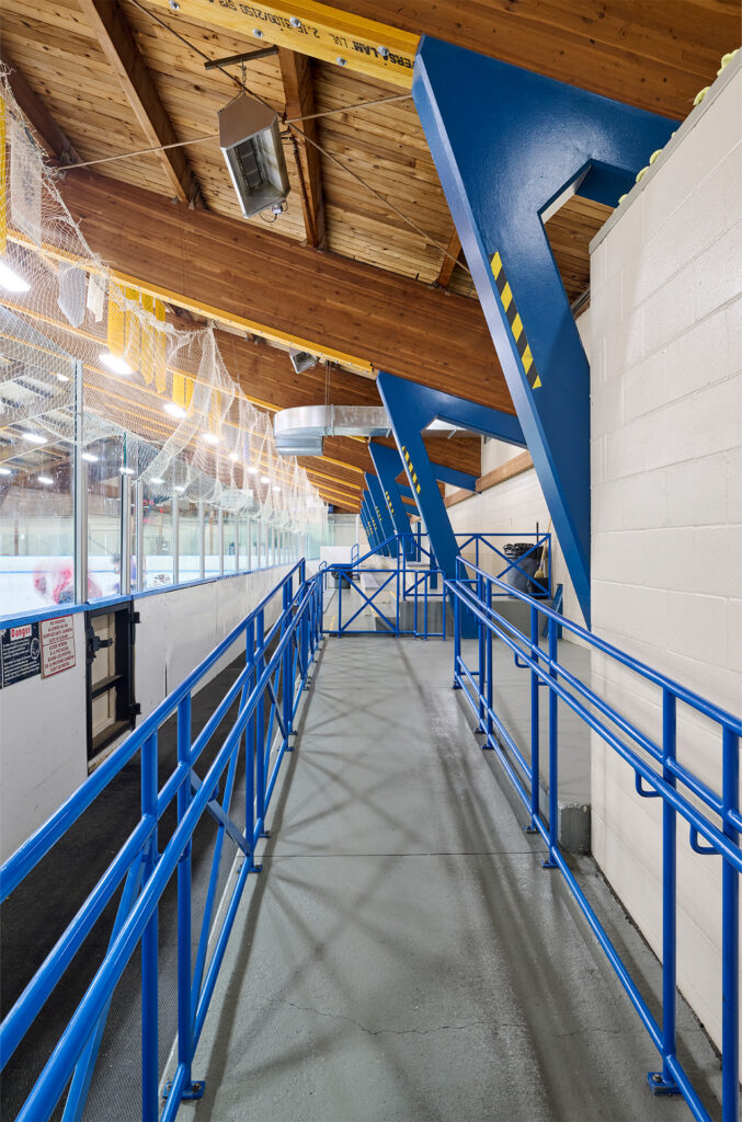 Side view of Fred Barrett Arena's seating with blue railings and exposed wooden ceiling