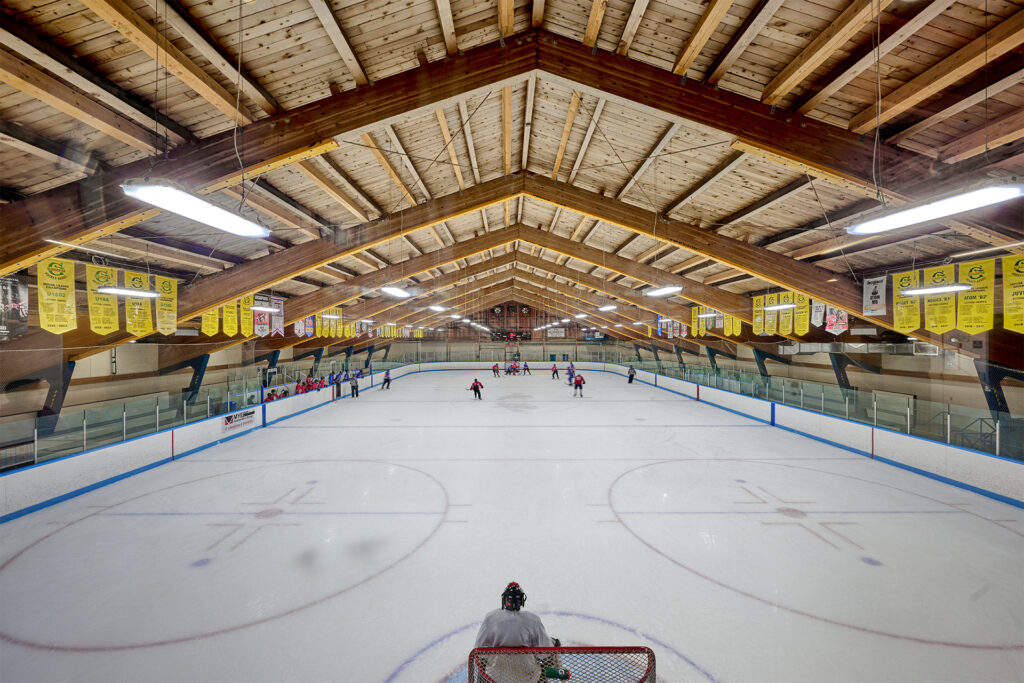 A well-lit indoor ice hockey rink showcases a game in progress