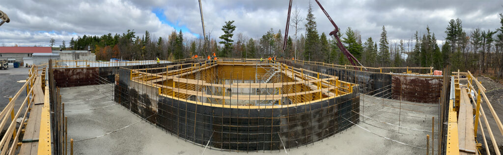 A panoramic view of a circular construction site with concrete walls and wood forms