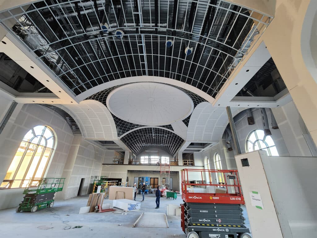 Interior view of St. Joseph Orthodox Church under renovation, showcasing exposed ceiling infrastructure and scaffolding