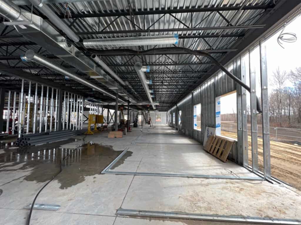 An industrial interior under construction with exposed metal beams, ductwork, and partial walls