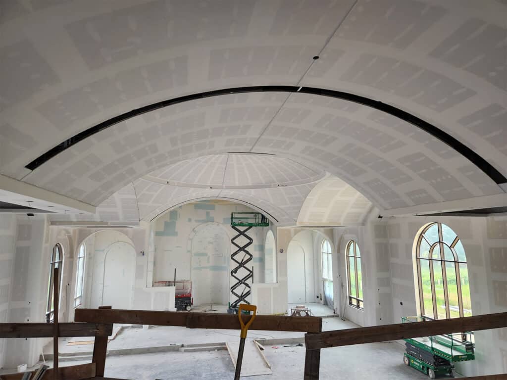 Interior of St. Joseph Orthodox Church showing vaulted ceilings and arched windows, with construction equipment and scaffolding indicating ongoing work