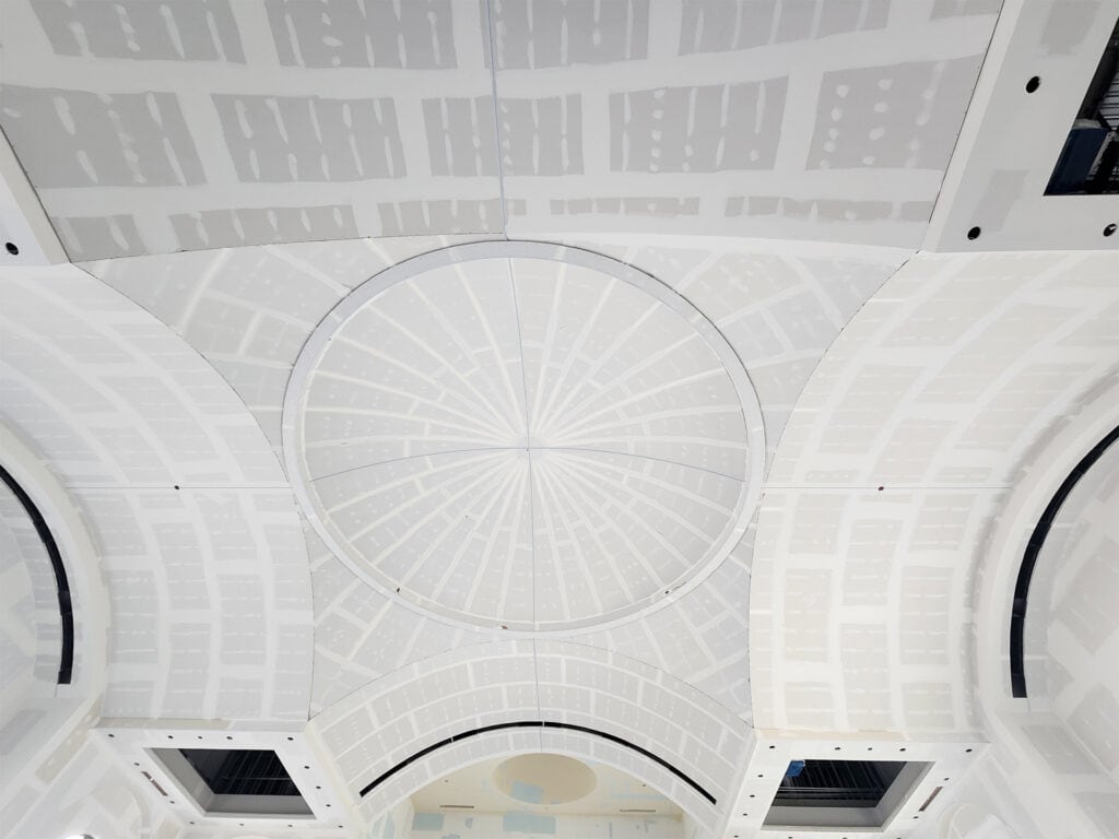 Symmetrical view of the white, radial-patterned dome ceiling inside St. Joseph Orthodox Church, with arched windows and architectural details