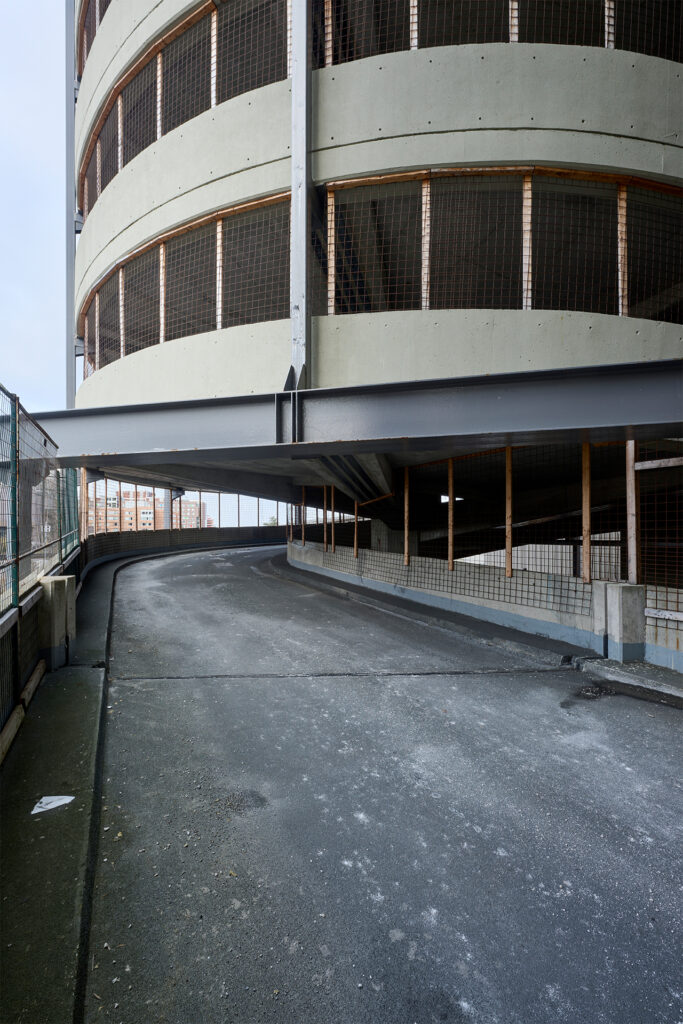 Exterior view of the circular Carleton University Parking 9 structure with mesh fencing and concrete ramps