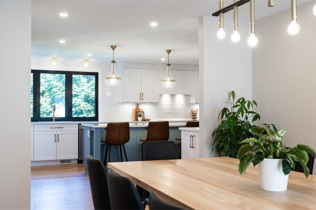 A bright, contemporary kitchen with white cabinetry, dark-framed windows, and elegant pendant light
