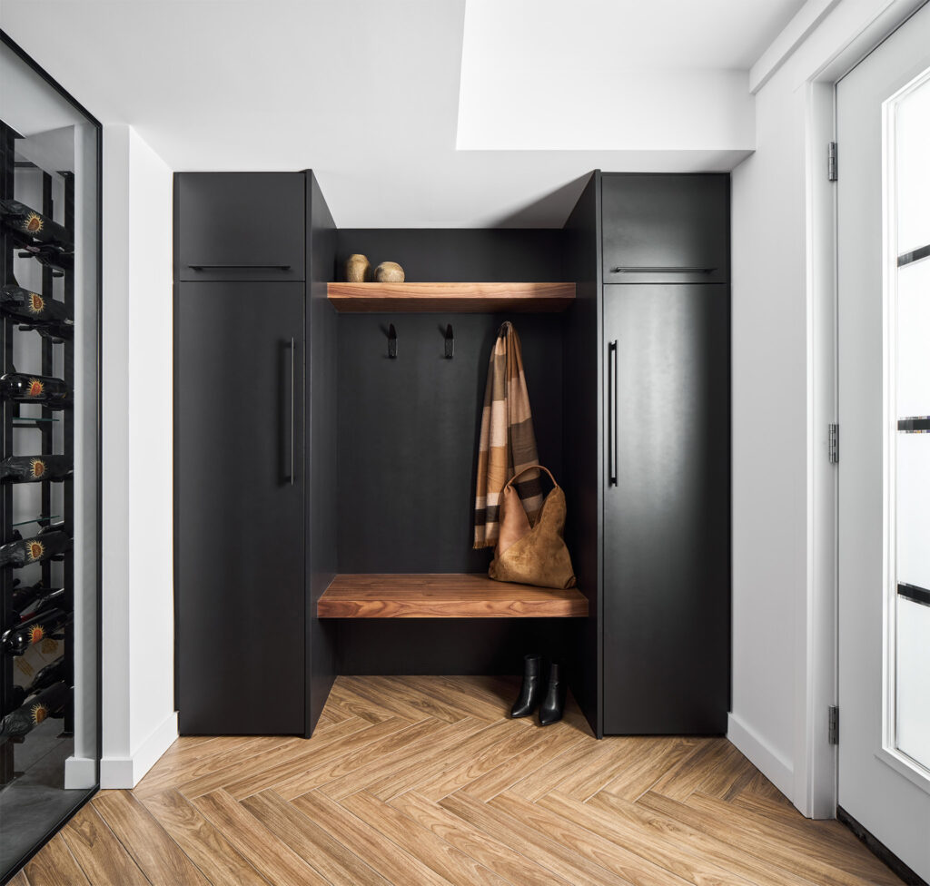 Modern entrance closet area featuring a built-in bench with wooden detailing, storage space, and herringbone patterned flooring