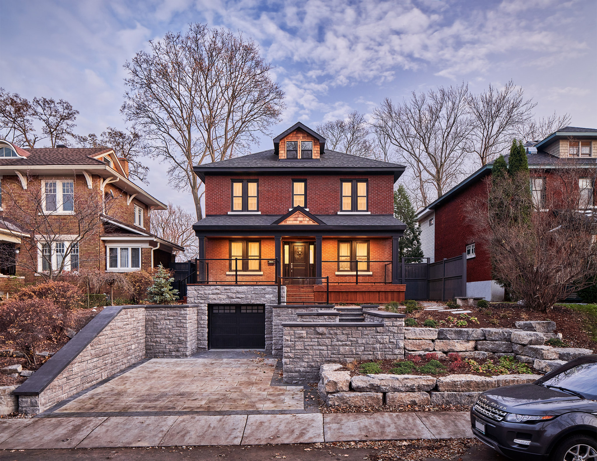 Renovated two-story brick home with a black garage door and stone landscaping, part of the Broadway Renovation project